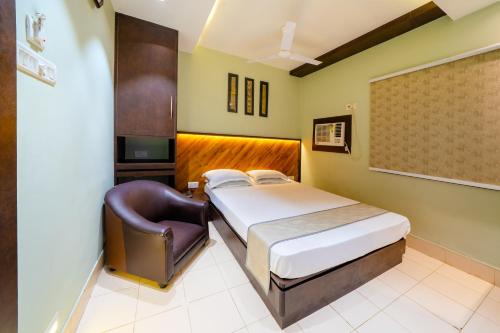 a hotel room with a bed and a chair at Hotel Dolphin Puri in Puri