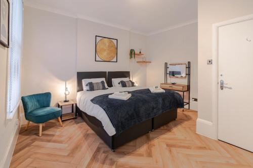 ブライトン＆ホーブにあるBeachfront, 2-bedroom, Sleeps 5, long staysのベッドルーム1室(ベッド1台、青い椅子付)