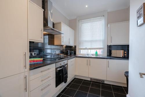 a kitchen with white cabinets and black tile floors at 2-bedroom, Sleeps 4, long stays in Brighton & Hove