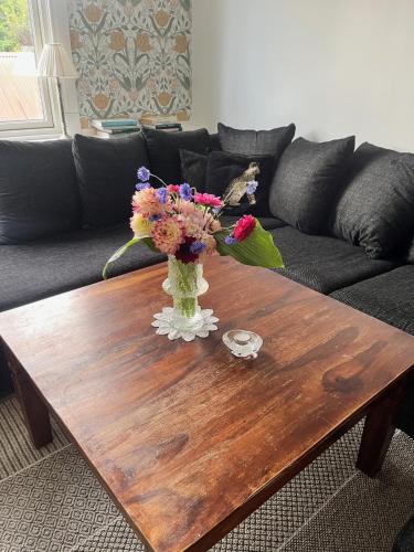 a vase of flowers on a wooden coffee table at Kulla Skola in Veddige