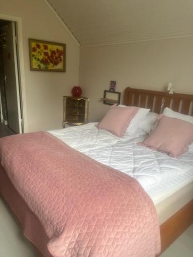 a bed with pink and white sheets and pink pillows at Kulla Skola in Veddige