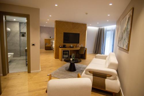a living room with a couch and chairs and a television at White Hill Hotel, SPA & Conferences in Durrës