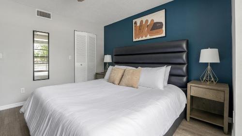 a bedroom with a large white bed with a blue wall at Landing Fort Myers - Forestwood in Fort Myers