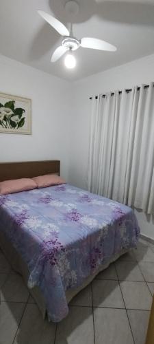 Un dormitorio con una cama y un ventilador de techo. en Condomínio edifício cannes, en Praia Grande
