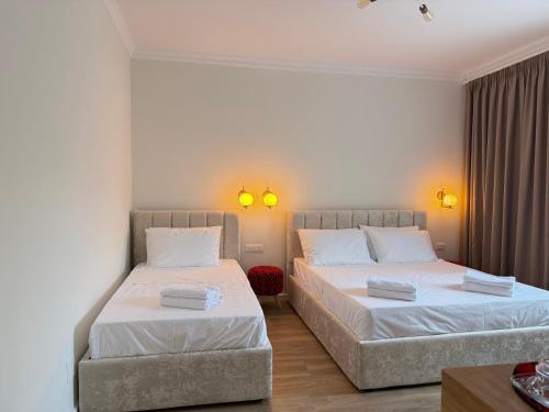 two beds in a hotel room with two lamps at Museum Boutique Hotel Tirana in Tirane