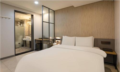 a bedroom with a large white bed and a bathroom at Hotel 99 Prestige in Seoul