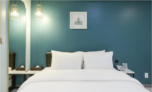 a blue bedroom with a large bed with white pillows at Hotel 99 Prestige in Seoul