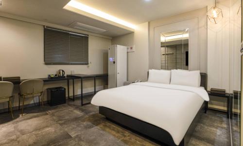 a bedroom with a white bed and a kitchen at Hotel 99 Prestige in Seoul