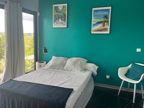 a bedroom with a bed and a blue wall at Latitude vue unique in Les Trois-Îlets