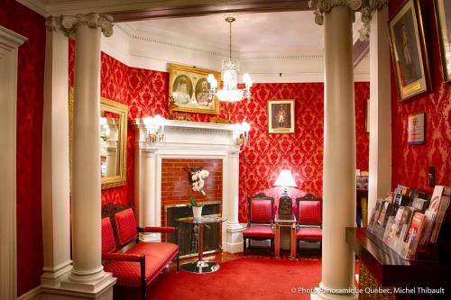 a red living room with red chairs and a fireplace at Le Chateau de Pierre in Quebec City