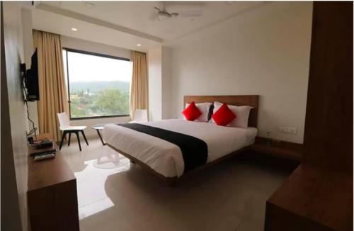 a bedroom with a bed with red pillows and a window at The Orange Flag - Renuka Hotel in Waluj Buzurg