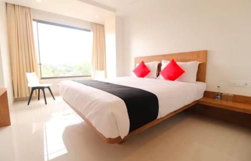 a bedroom with a large bed with red pillows at The Orange Flag - Renuka Hotel in Waluj Buzurg