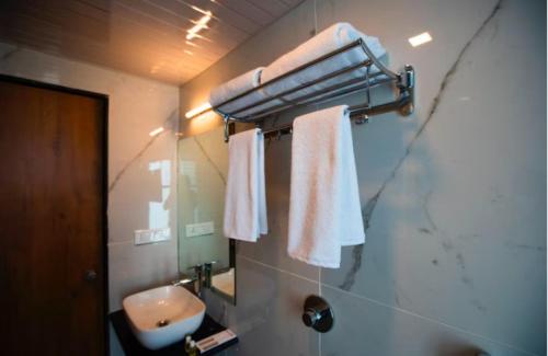 a bathroom with a sink and a mirror and towels at The Orange Flag - Renuka Hotel in Waluj Buzurg