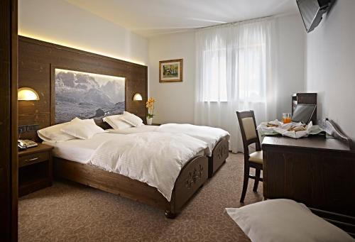 a bedroom with a large bed and a desk and a computer at Hotel Europa in Madonna di Campiglio