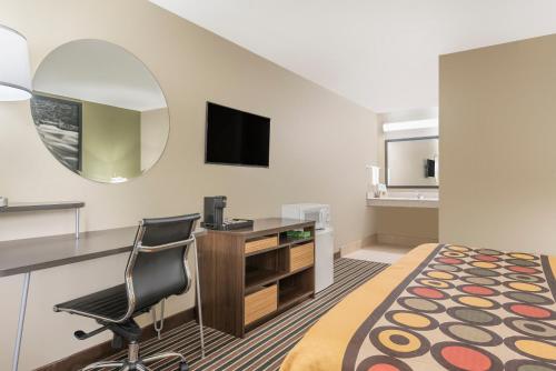 a hotel room with a bed and a desk and a mirror at Super 8 by Wyndham Bryant Little Rock Area in Bryant