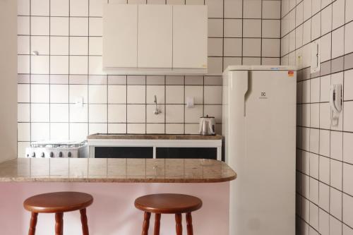 a kitchen with two stools and a white refrigerator at Apartamento a 350 metros da Praia do Morro in Guarapari