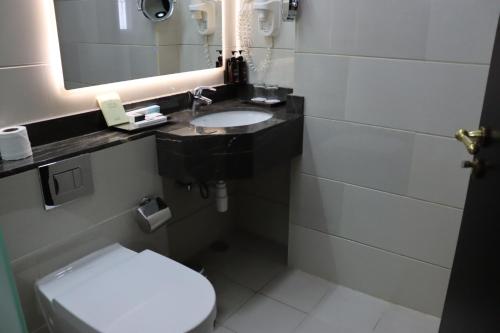 a bathroom with a toilet and a sink and a mirror at Raviz Center Point Hotel in Dubai