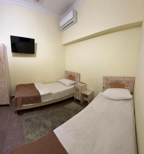 two beds in a room with a tv on the wall at CA Yerevan Hotel in Yerevan
