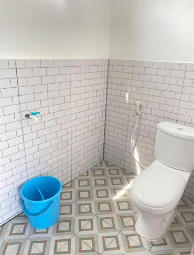 a bathroom with a toilet and a blue bucket at Warm kabin dieng in Diyeng