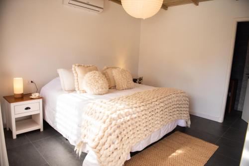 a bedroom with a white bed and a nightstand with a lamp at La Posadita in José Ignacio