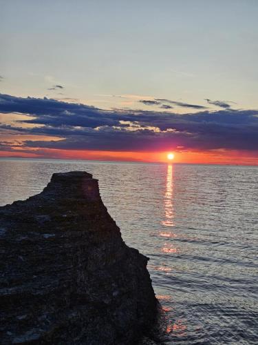 a sunset over the ocean with a rock in the water at Trevlig fritidshus på Norra Öland in Löttorp