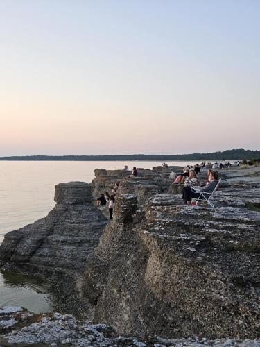 a group of people sitting on rocks near the water at Trevlig fritidshus på Norra Öland in Löttorp