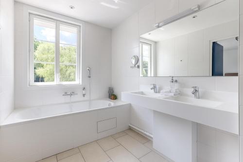 a white bathroom with two sinks and a tub at La Coudraie - Proche de Disneyland in Montévrain