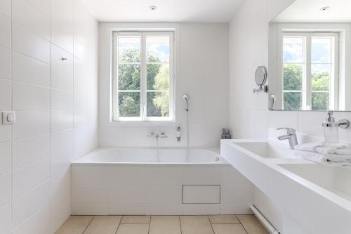 a white bathroom with a tub and two sinks at La Coudraie - Proche de Disneyland in Montévrain
