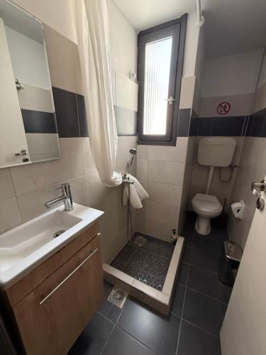 a bathroom with a sink and a toilet and a window at Above Apartments near the Airport in Artemida
