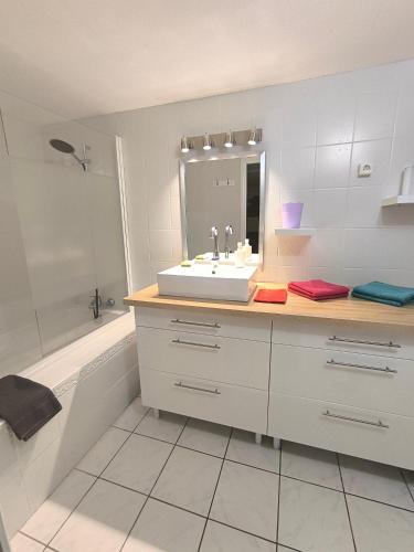 une salle de bain avec un lavabo, une baignoire et un miroir dans l'établissement T2 jusqu'à 4 personnes en rez-de-jardin de maison, avec piscine, draps et serviettes de toilette fournis, à Argelès-sur-Mer