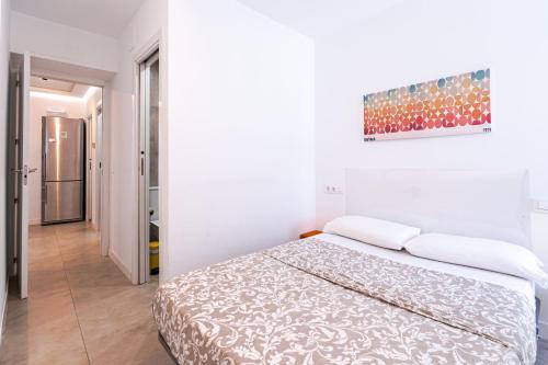 a white bedroom with a bed and a painting on the wall at Tu casa en Madrid in Madrid