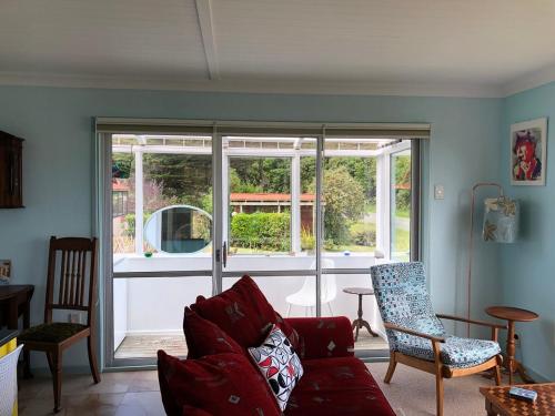 a living room with a red couch and a window at Butterfield Beach House Stewart Island incl car in Oban