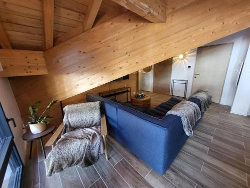 - un grand canapé bleu dans une chambre dotée de plafonds en bois dans l'établissement Appartement Chamois avec Wifi et Garage à Montgenèvre - FR-1-266-246, à Montgenèvre