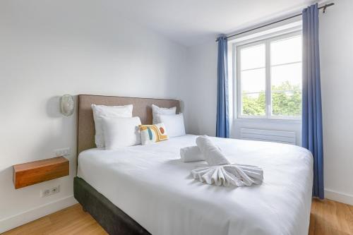 a bedroom with a large white bed with a window at La Coudraie - Proche de Disneyland in Montévrain