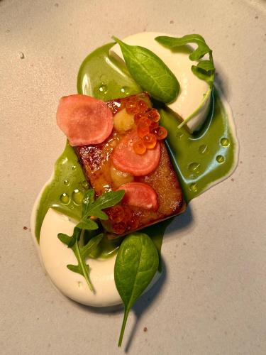 a plate with a piece of food with sauce and vegetables at Taurus Tell Gasthaus Andermatt in Andermatt