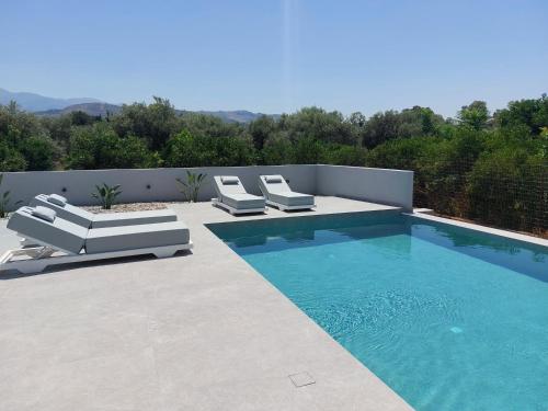 a swimming pool with two lounge chairs and a swimming pool at Hesperian Luxury Villas in Chania Town