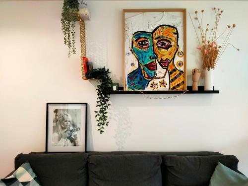 a living room with a couch and a painting on the wall at Le cosy avec climatisation, terrasse et parking privatif in Annemasse