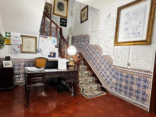 an office with a desk and stairs with drawings on the wall at HOTEL BOUTIQUE a ESPLANADA in Castelo Branco