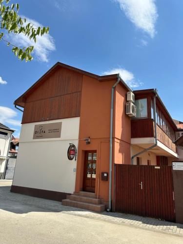 a orange and white building with a fence at Véndiófa szálláshely in Kecskemét
