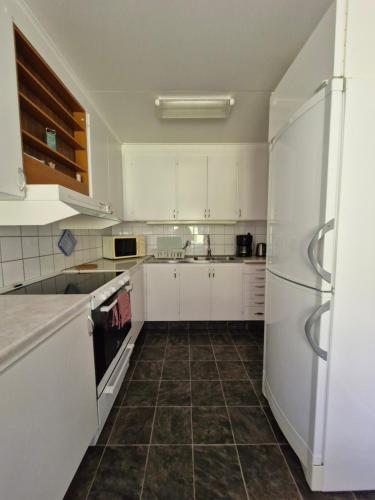 a kitchen with white cabinets and a tile floor at Nordbakks holiday apartments in Frostviken, Gäddede in Gäddede