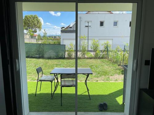 a table and two chairs outside a window at T2 cosy avec terrasse et jardin à Belley in Belley
