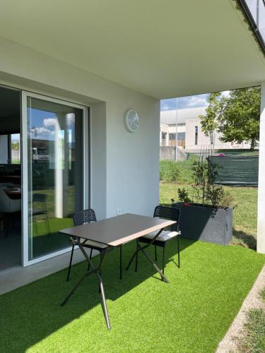 a table and chairs on a patio with grass at T2 cosy avec terrasse et jardin à Belley in Belley