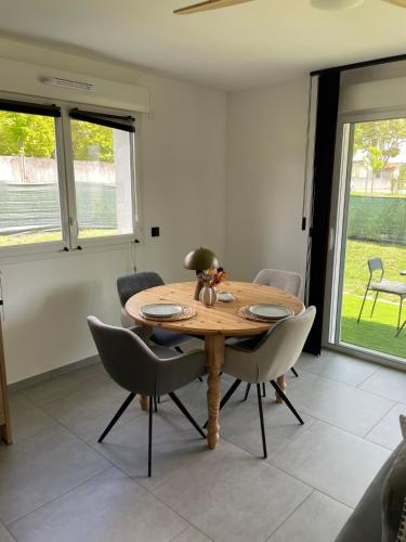 a dining room with a wooden table and chairs at T2 cosy avec terrasse et jardin à Belley in Belley