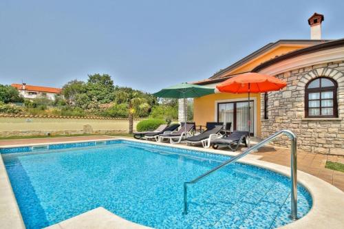 a pool with umbrellas and chairs and a house at Villa Morena by Briskva in Kaštel
