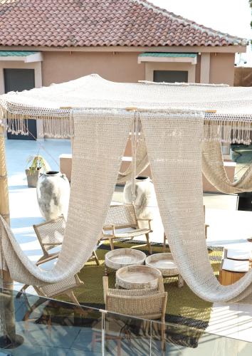 a hammock and chairs under a white umbrella on a patio at Hotel Platinium Dhermi in Vlorë