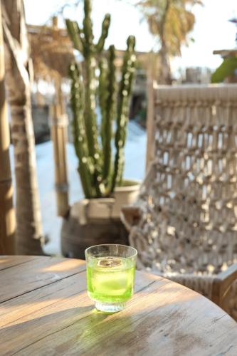 a glass of green liquid sitting on a wooden table at Hotel Platinium Dhermi in Vlorë