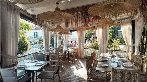 a restaurant with tables and chairs and large windows at Hotel Platinium Dhermi in Vlorë