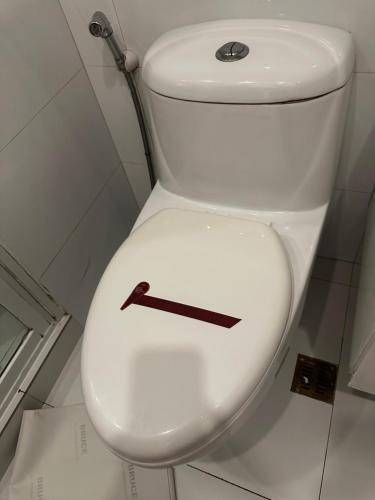 a white toilet with a black arrow on it at A place to stay in Iloilo City