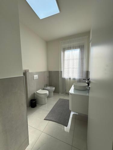 a white bathroom with two toilets and a window at B&B Orio Affittacamere Foresteria Lombarda in Grassobbio