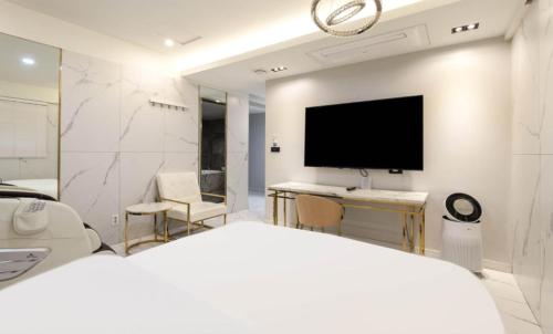 a white bedroom with a television and a bed at Hotel 99 Prestige in Seoul